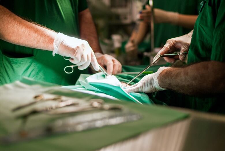 A shot of surgeons holding instruments near a patient.