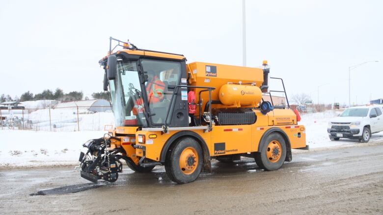 a large yellow vehicle filling potholes on the street