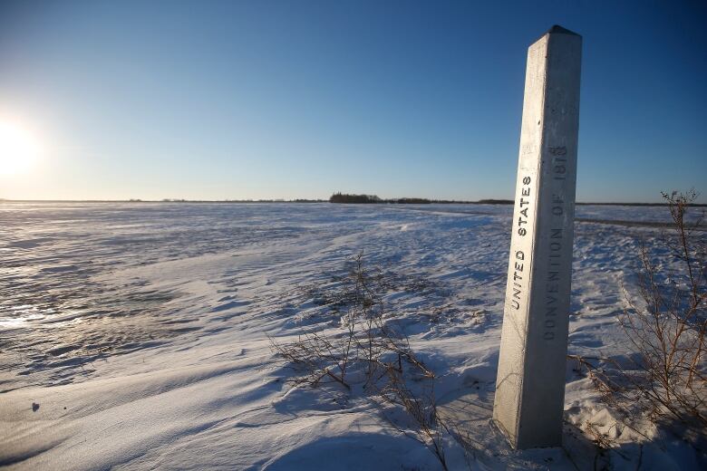 A snowy field with a concrete border marker in one corner.