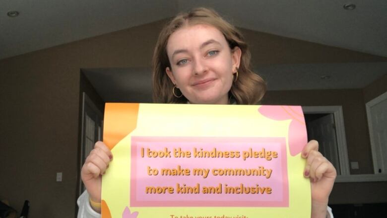 A photo of a woman holding a sign.