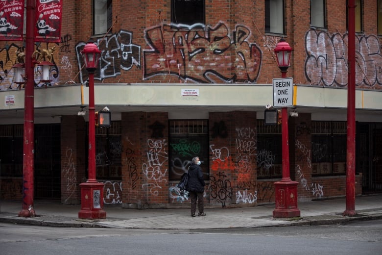 A red brick building is covered with various types of graffiti.