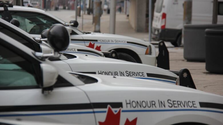 A row of white cars with police insignia