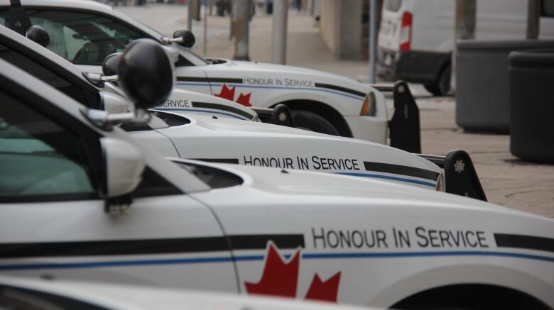 A row of white cars with police insignia