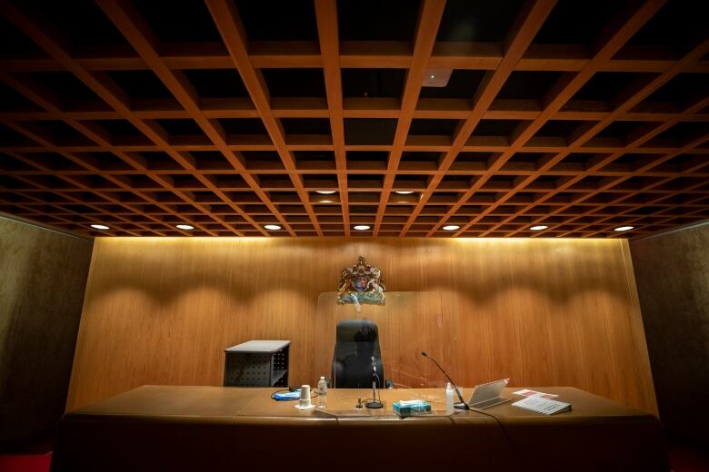 A courtroom interior with a crest of British Columbia behind a judge's desk.