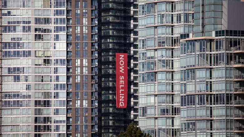 A 'now selling' banner is draped along the side of an apartment building.