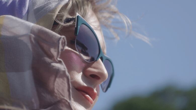 Still frame from the film Framing Agnes. Closeup shot of Zackary Drucker in a headscarf and sunglasses.