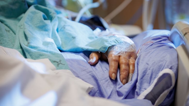 The hand of a COVID-19 patient on a ventilator is pictured in the intensive care unit of Humber River Hospital, in Toronto, on Jan. 25, 2022.