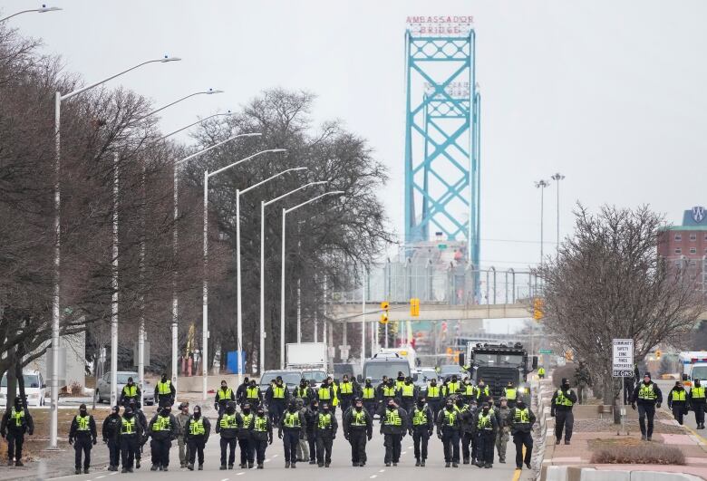 Police line up to remove protestors during Ambassador Bridge blockade