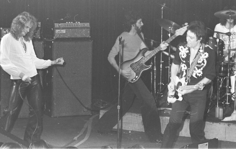 Black and white photo of band members playing at a concert