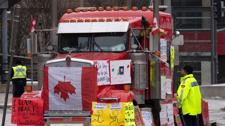 A police officer speaks with a trucker parked in Ottawas downtown core Feb. 16, 2022. Police were handing out paper notices that morning reminding people blocking streets is illegal, along with making sure they knew about recent new powers. 