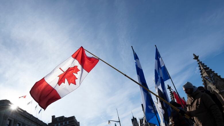 An upside down Canada flag on a handheld pole near a legislature.