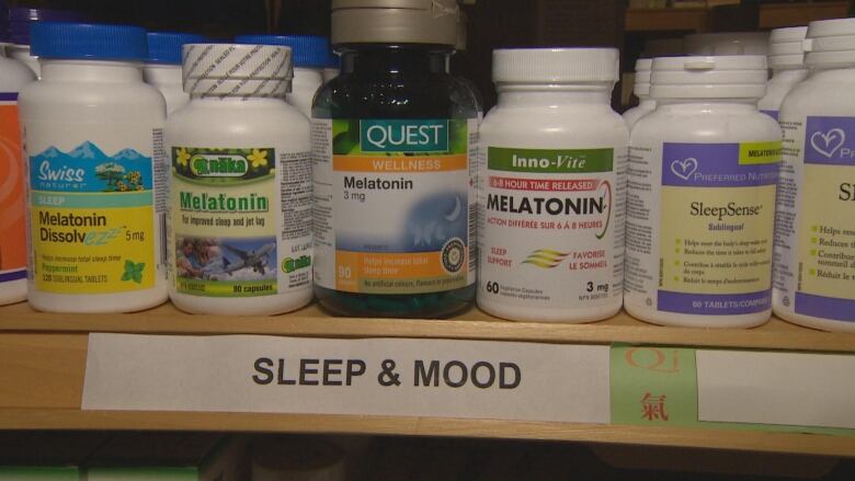 A row of melatonin containers sit on a shelf.