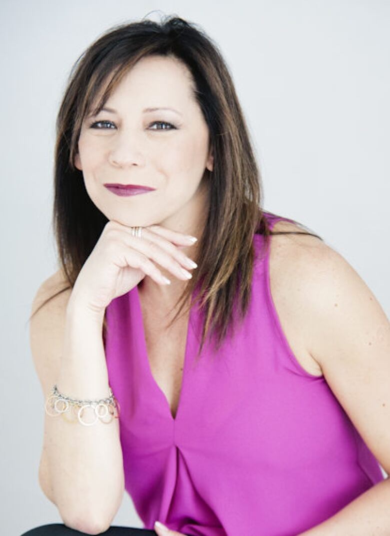 A woman poses for a photo in front of a white background.