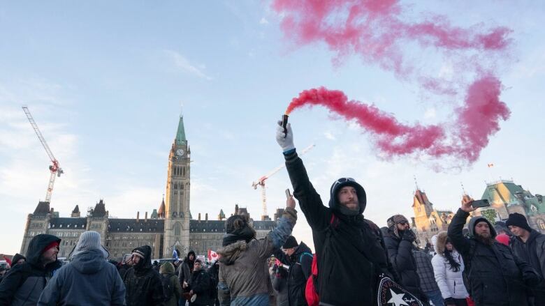 A man waves a can of red smoke in the air outside the parliament buildings in Ottawa.