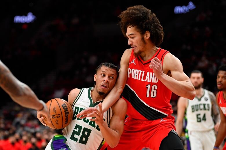 Two players on a basketball court. One is a Bucks player holding the ball. The other is a Trail Blazers player