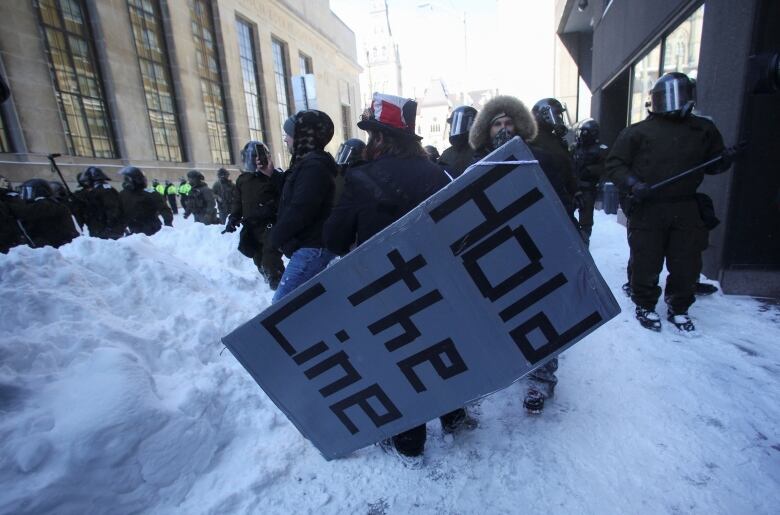 A demonstrator carries a sign, as Canadian police work to restore normality to the capital while trucks and demonstrators continue to occupy the downtown core for more than three weeks to protest against pandemic restrictions in Ottawa, Ontario, Canada, February 19, 2022.