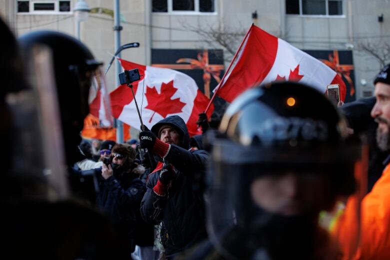 A Freedom Convoy protester uses a camera on a selfie stick as police enforce an injunction against protesters, some who have been camped in their trucks near Parliament Hill for weeks, on Feb. 19, 2022.