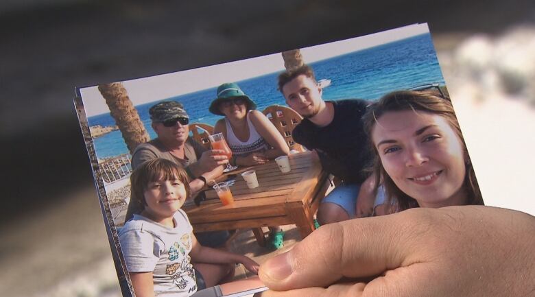 Someone holding a photo in their hand of people at the beach