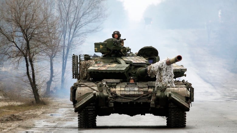 Two Ukrainian service men ride on a tank.