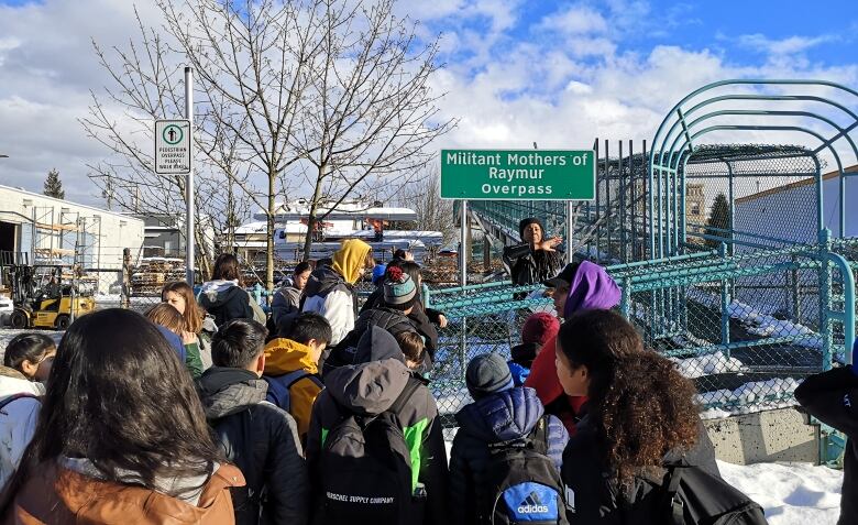 A crowd of people about to walk across the Militant Mothers of Raymur overpass