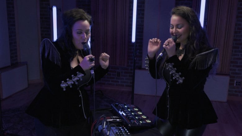 PIQSIQ, two Inuit sisters from Yellowknife hold microphones while performing inside a recording studio.