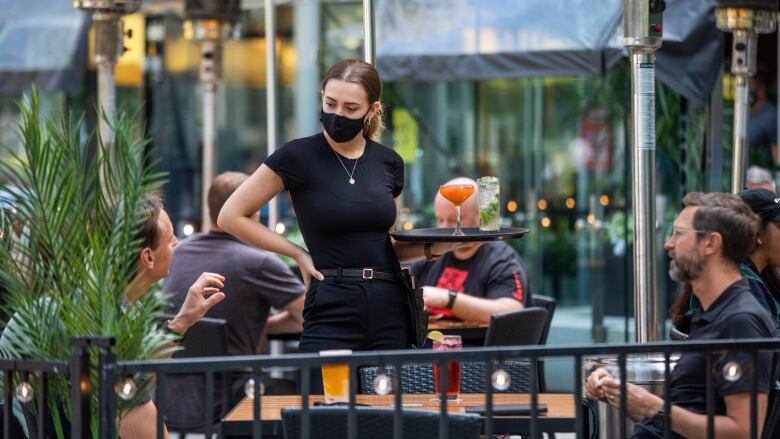 A server takes an order from patrons at a restaurant in downtown Vancouver, British Columbia on Tuesday, June 22, 2021. 