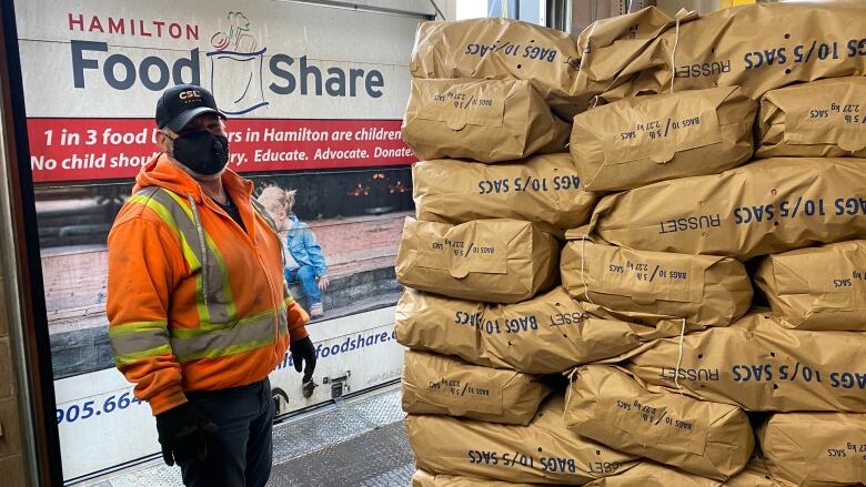 man stands by stack of potato bags