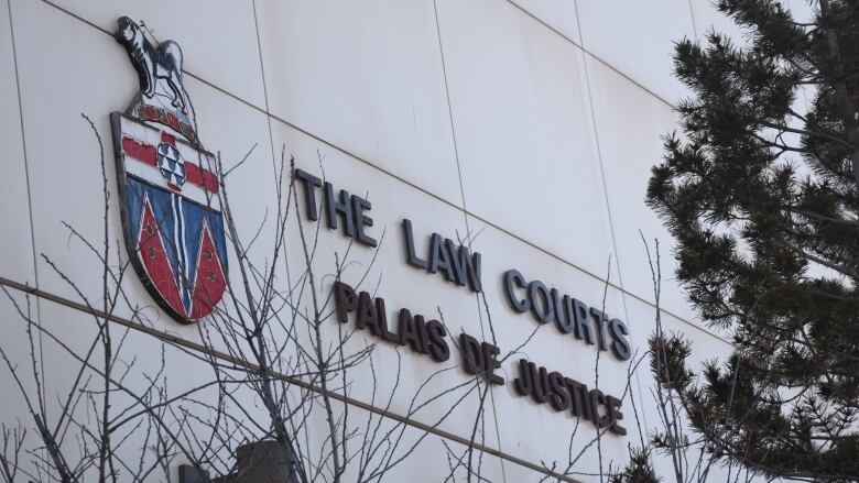 A close-up of the exterior wall of the courthouse in Whitehorse, Yukon, features a white wall with the Yukon coat of arms.