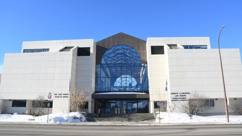 A building with large white tiled walls and a glass atrium in the centre.