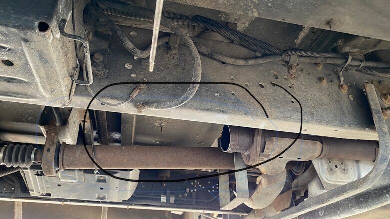 the underside of a vehicle showing the exhaust system and where a catalytic converter has been cut out