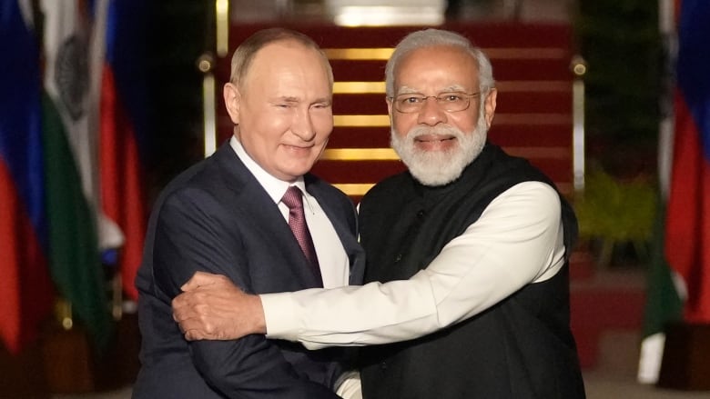 Two men pose for a photo as they shake hands. 