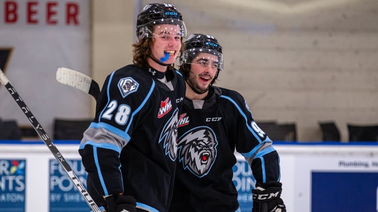 Two hockey players smile during a scrimmage.