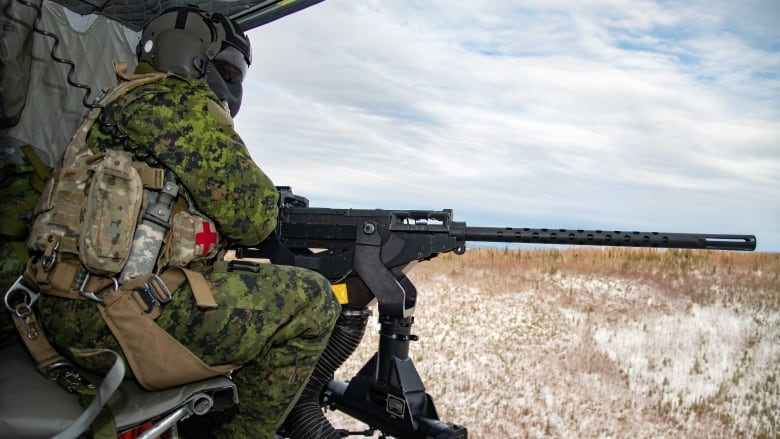 Corporal Nicolaus Lalopoulos, a Door Gunner with 408 Tactical Helicopter Squadron, mans a Browning M2 .50 Caliber Heavy Machine Gun on a CH-146 Griffon training flight during Joint Pacific Multinational Readiness Center 22-02 at Fort Wainwright, Alaska on March 8, 2022.