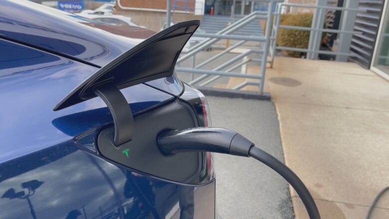 A charger is seen plugged into a blue electric car