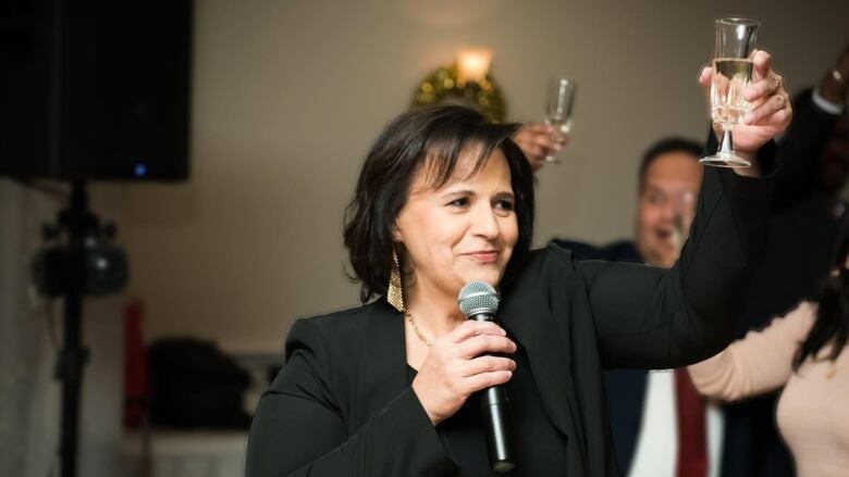 A woman at a social gathering raises a glass. 