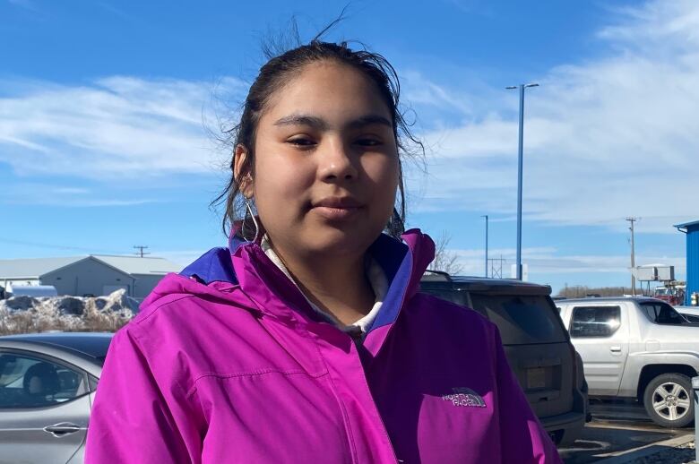 A woman wearing a purple windbreaker poses for a photo.