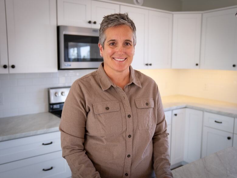 Person standing in a clean, white kitchen.