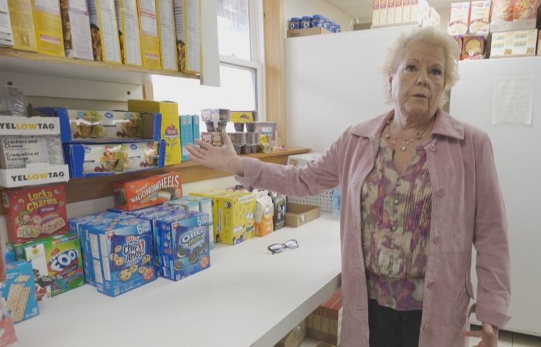 Woman gesturing to a counter filled with food 