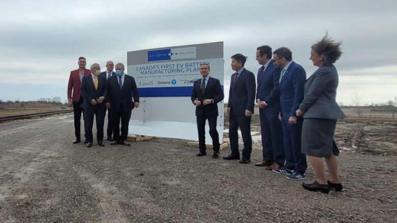 A line of people in front of an empty field that is the future site of Windsor's EV battery plant