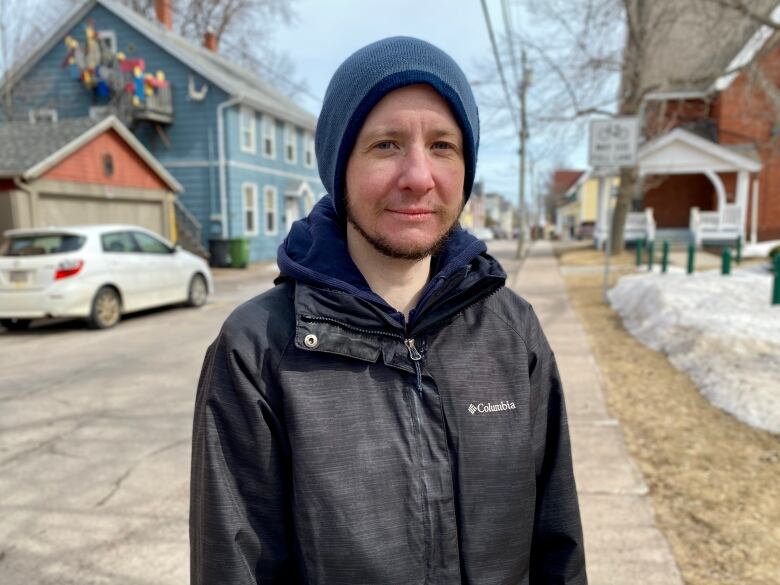 A short haired man in a toque looks at the camera