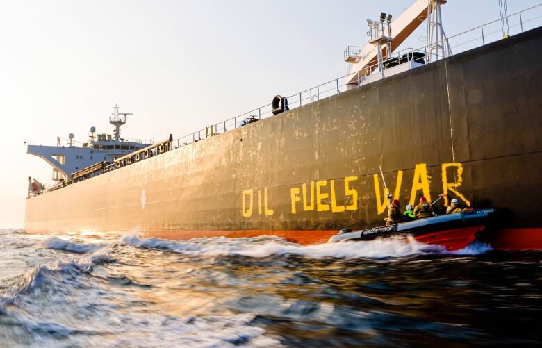 Activists of the environmental organization Greenpeace paint the words 'Oil fuels war' on the hull of a ship carrying Russian oil near the German island Fehmarn, Germany, Wednesday, March 23, 2022.