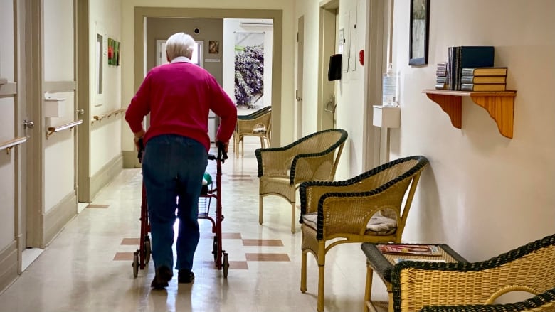 An old person walks down a hallway 