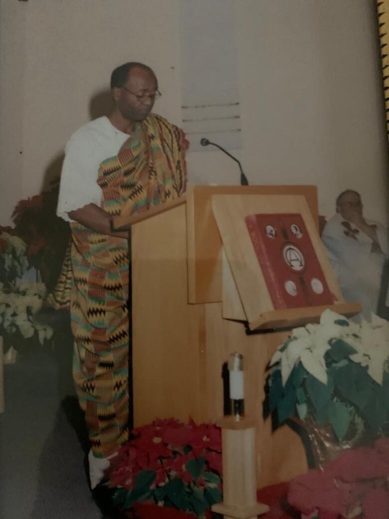 A Black man standing a podium with a mic