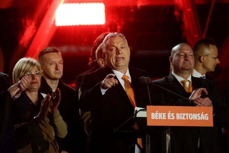 A man in a suit stands behind a podium.