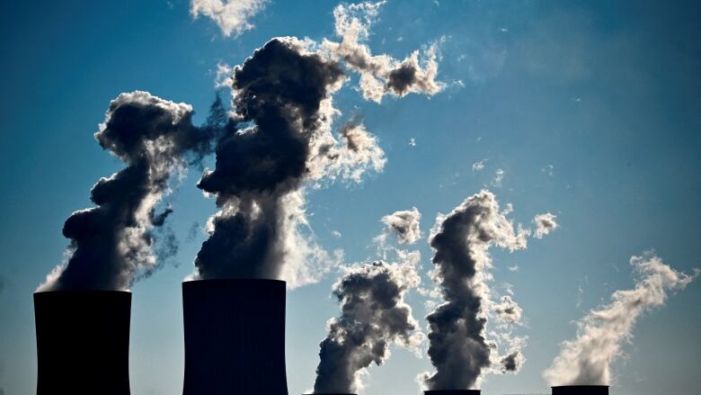 Smoke stacks with smoke rising out of them.