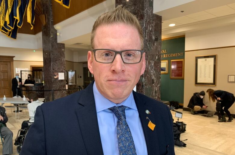 A smiling man wearing glasses and a suit