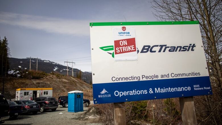 A BC transit sign has another sign covering part of it. The other sign reads 