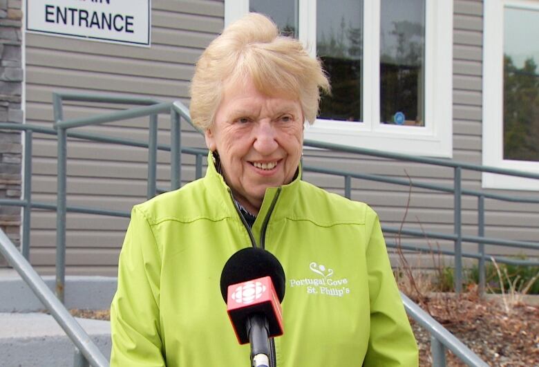 woman wearing light green jacket speaking in front of a microphone