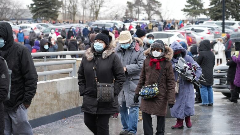 People wearing masks wait in a line.