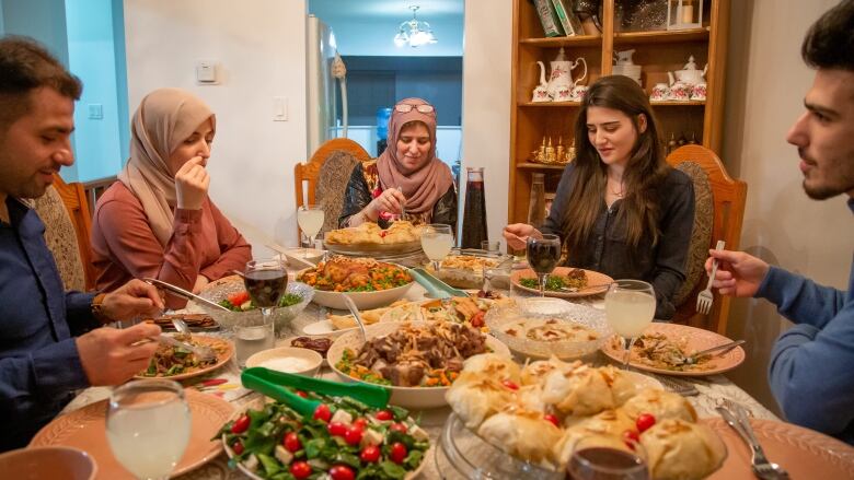 A family sits around a table prepared with food.